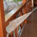close-up of power washing hose spraying railing