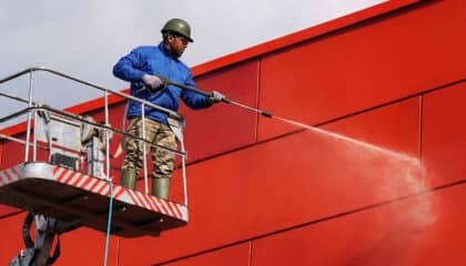man power washing side of building