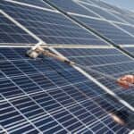 man using a cleaning tool on solar paneling