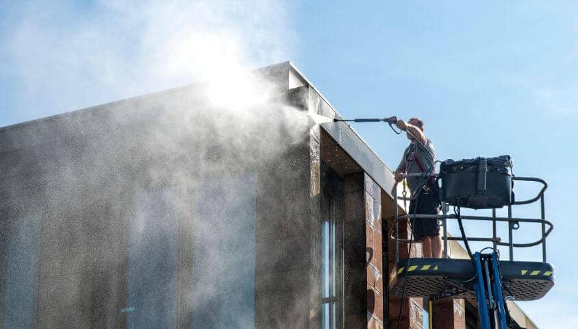 Man power washing a building