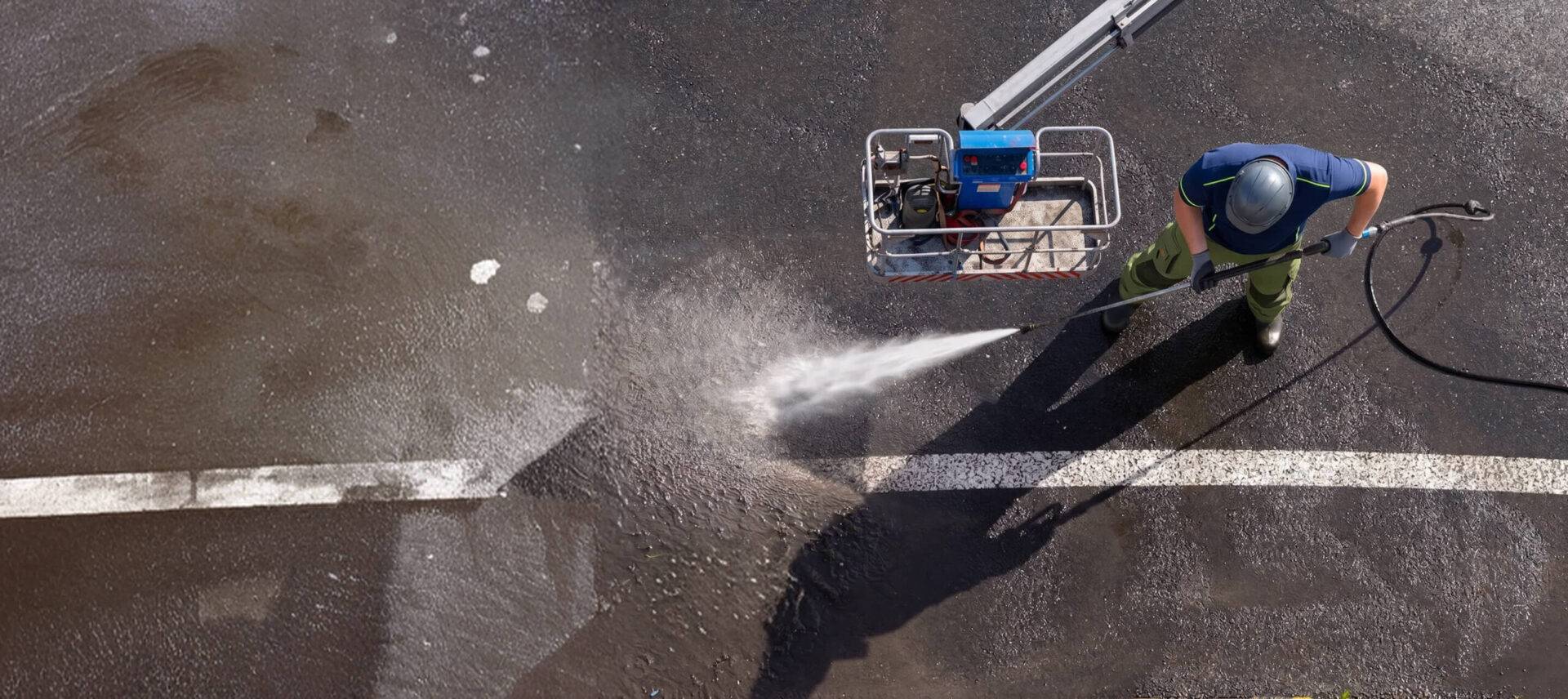 man power washing dirt and other grime off parking lot lines