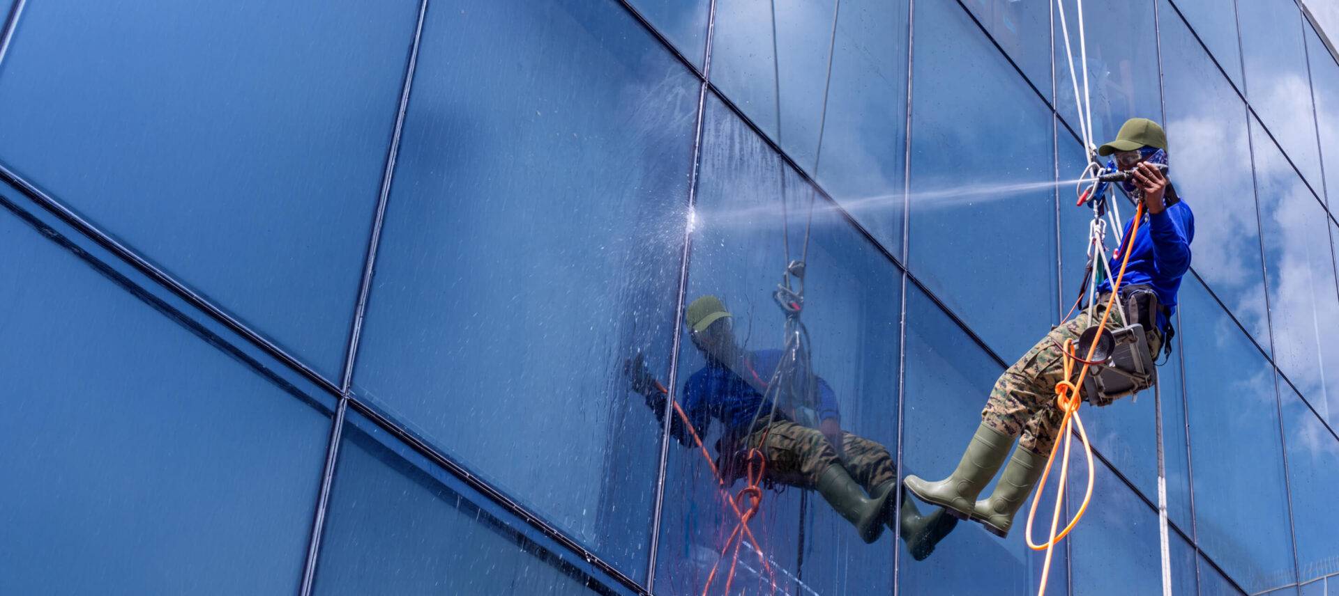 gentleman power washing windows on side of building