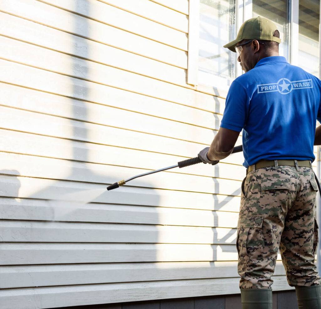 prop wash employee power washing side of house